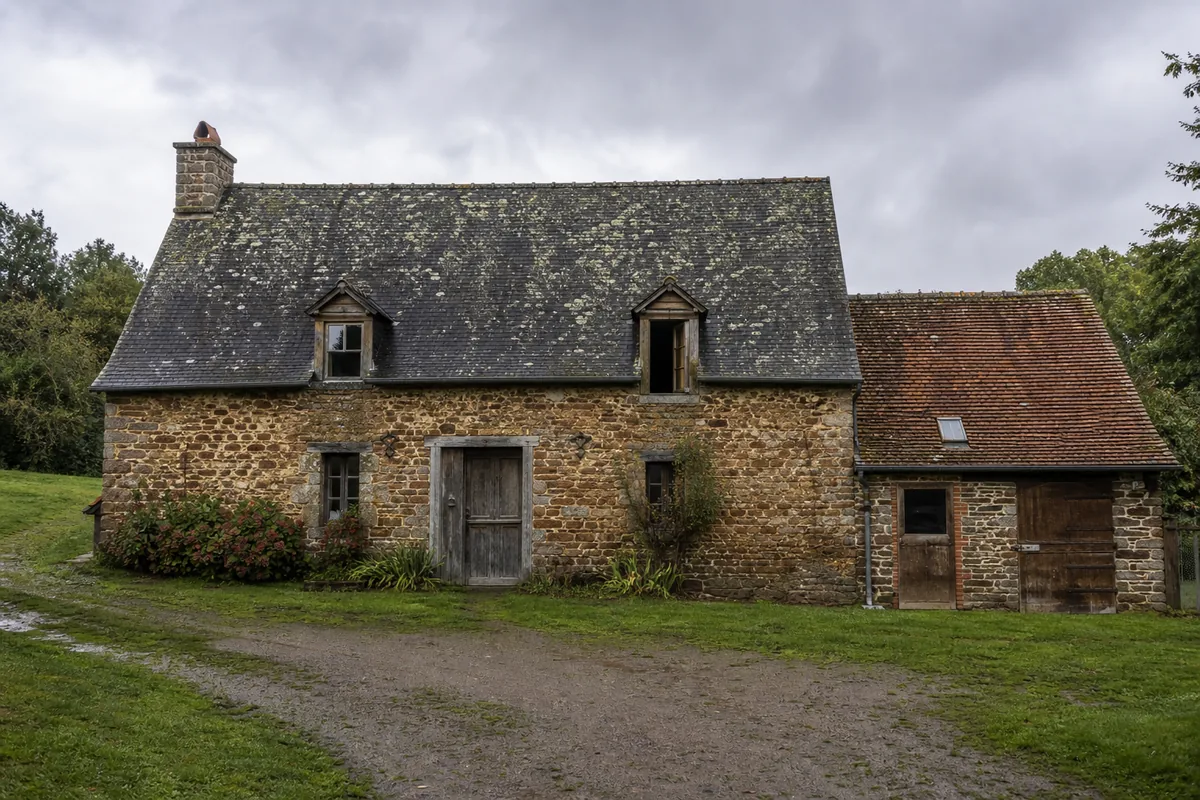 Longère sarthoise à forte pente couverte d’ardoise sous un ciel gris perle